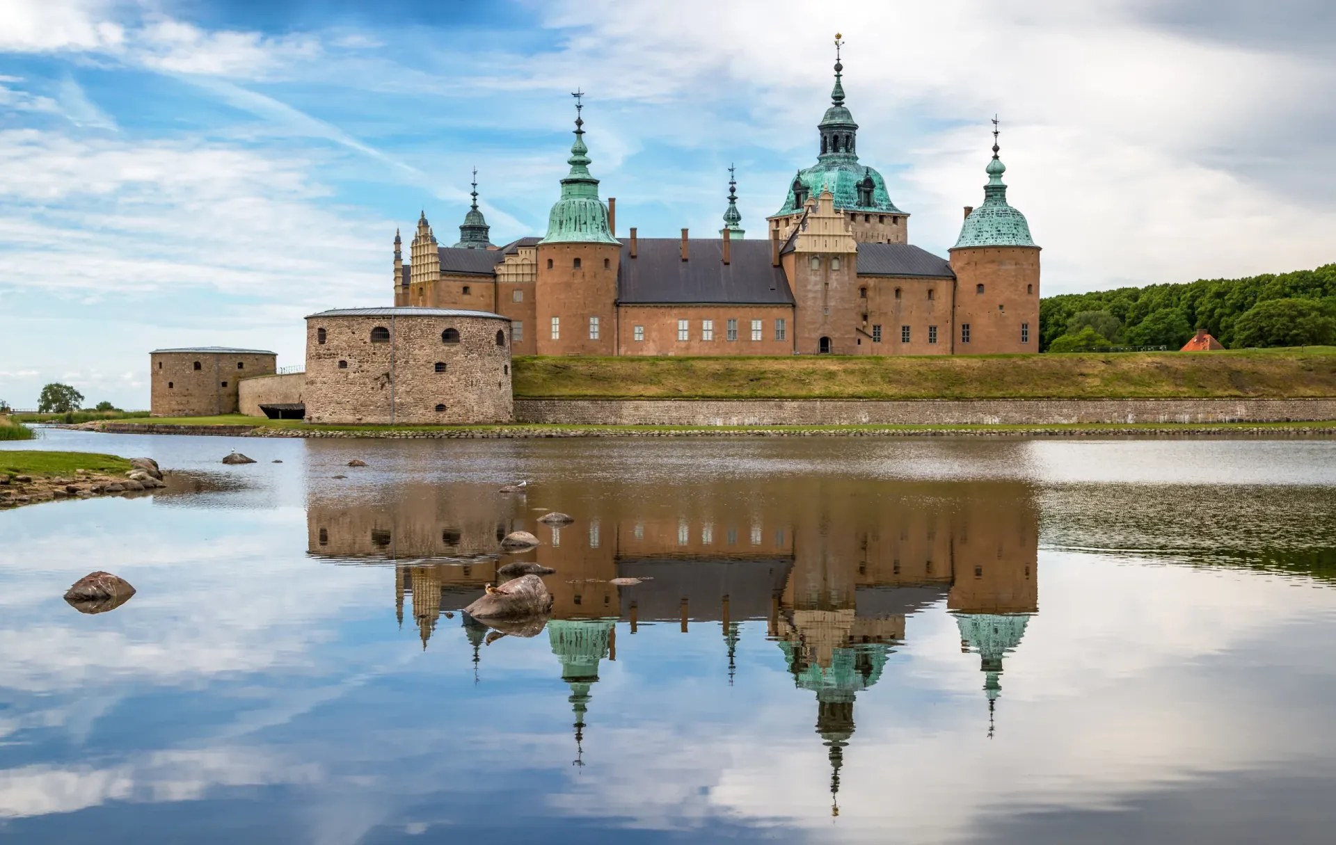 Kalmar slott speglas i det stilla vattnet en sommardag