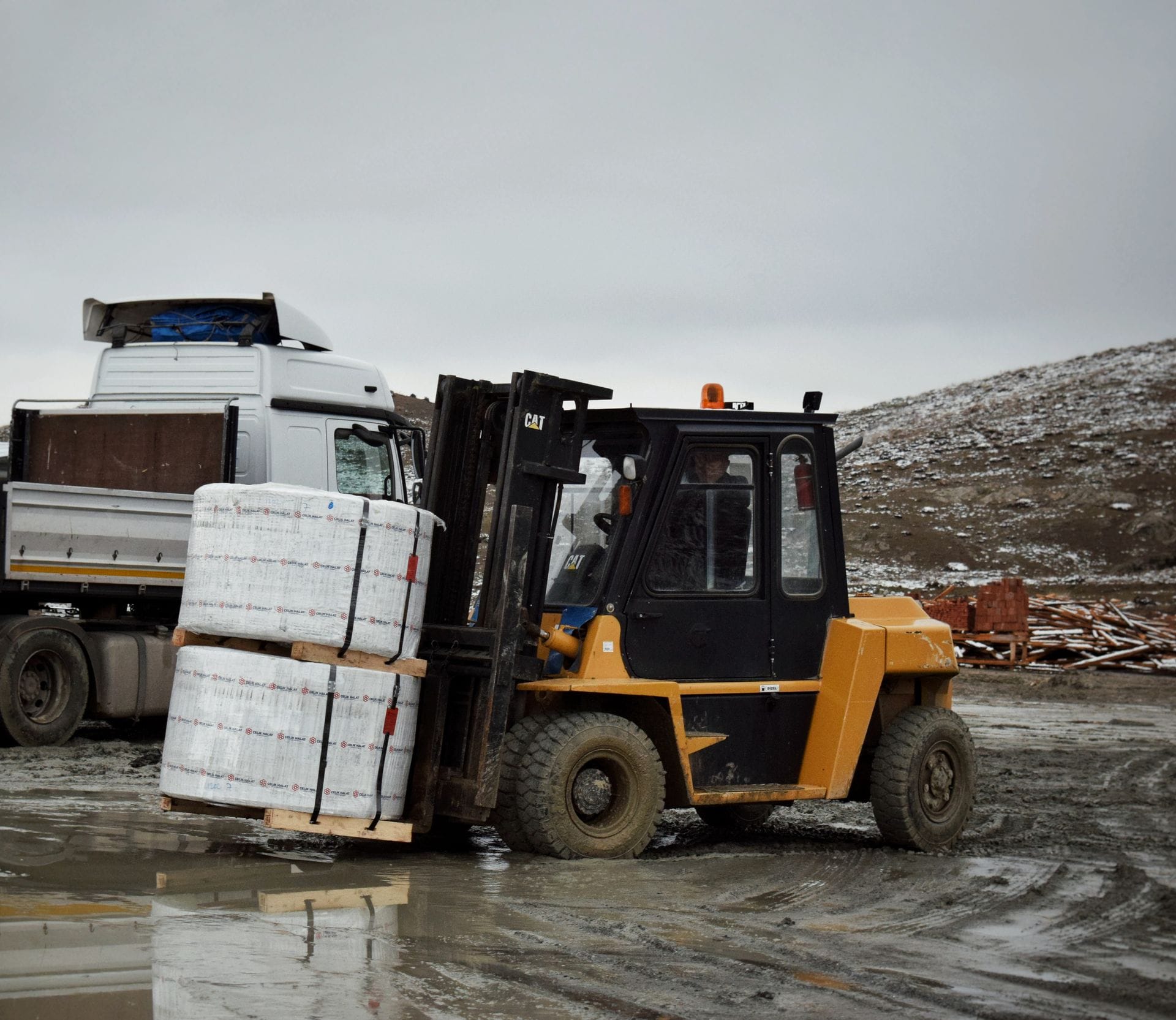 Gaffeltruck som lyfter en pall med gods på en industrigård